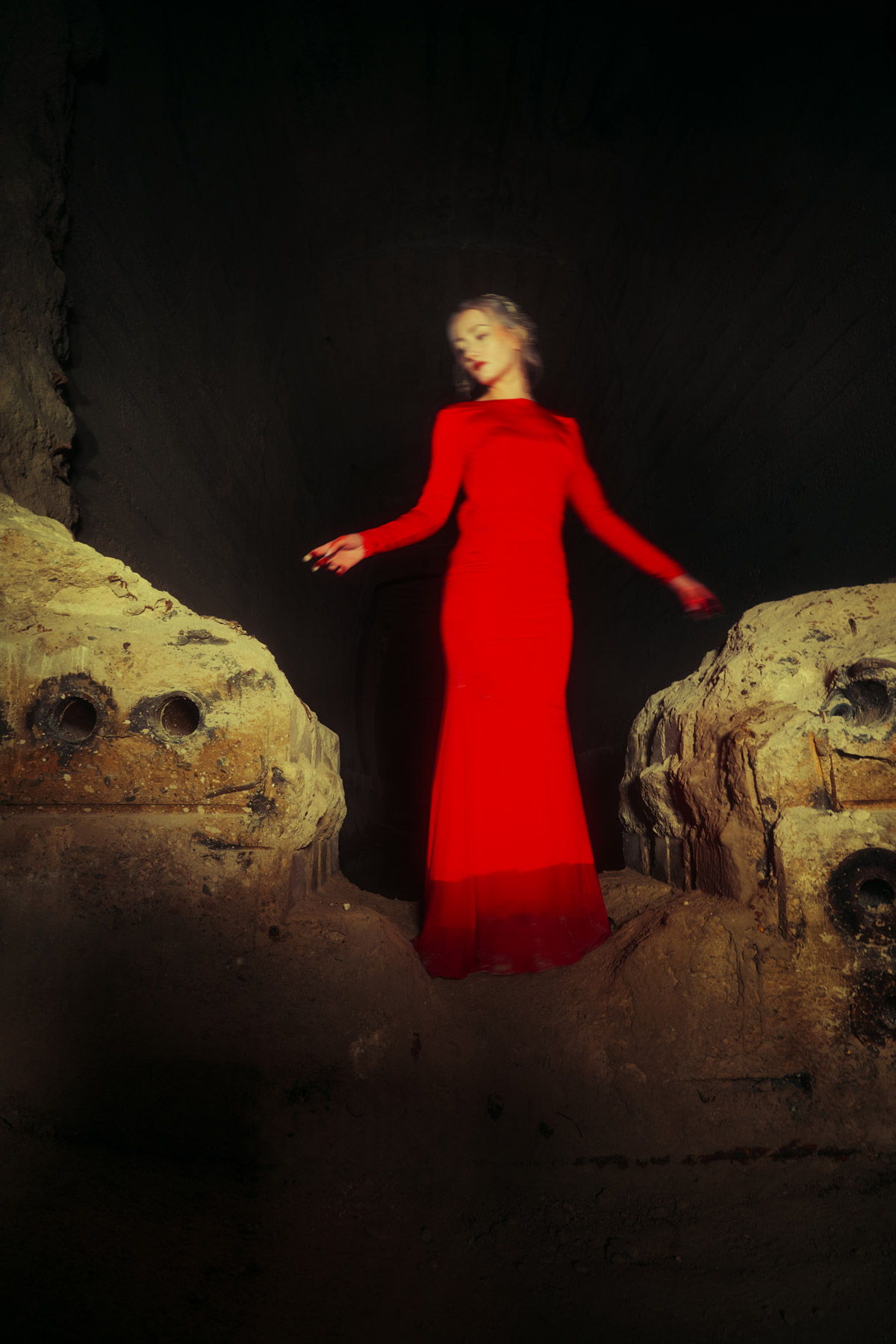 Junge Frau in einem roten Kleid steht zwischen zwei Felsen. Fotograf: Lea Kutschke, Geraldine Kutschke / TWIINZ.